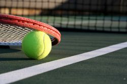 Tennis ball and racket next to the net